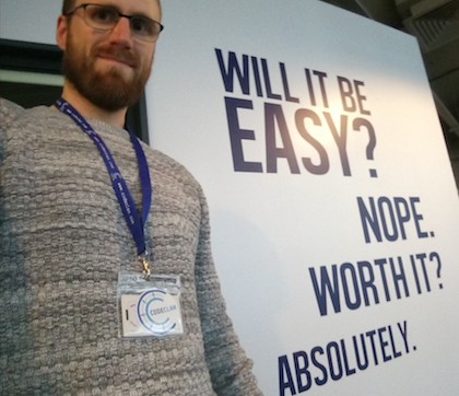 Callum against background of 'Wont be easy but worth it' slogan on wall